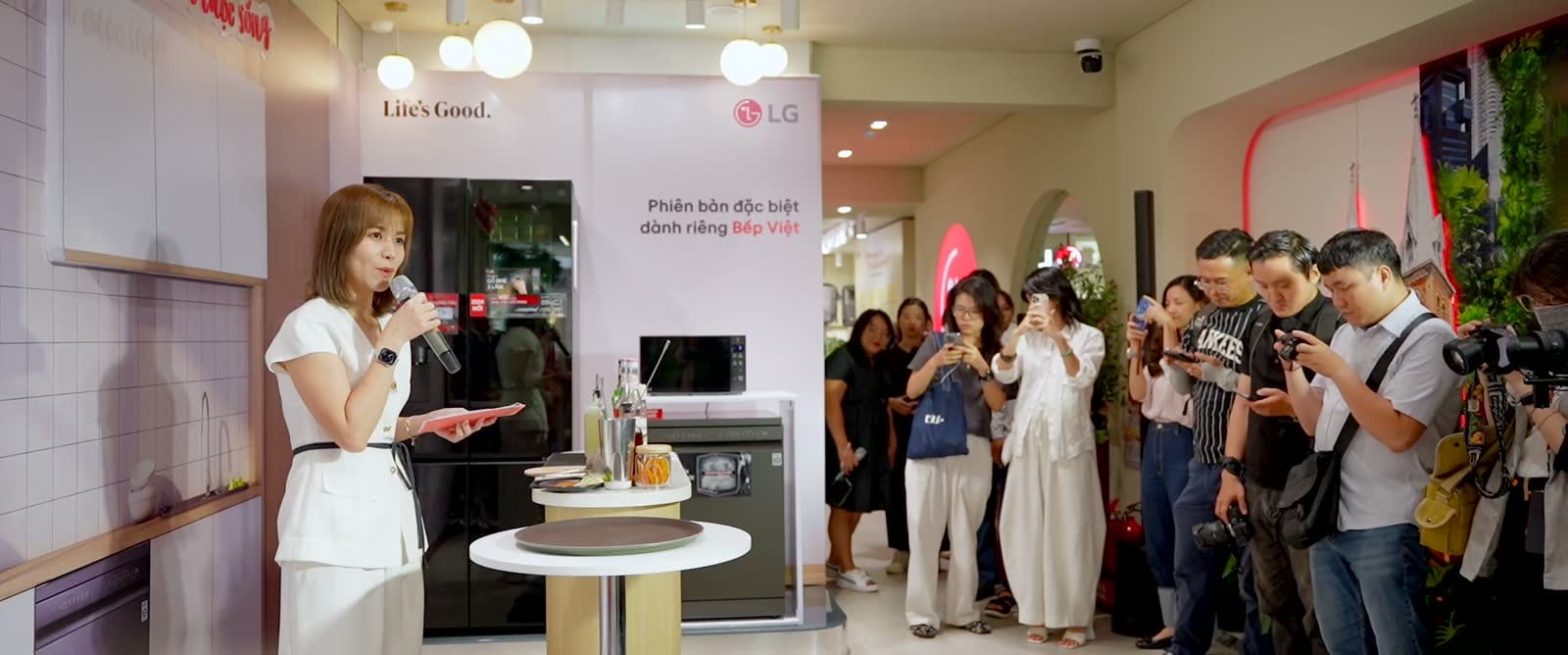 Đại diện LG cầm micro giới thiệu bếp và tủ lạnh trước nhóm phóng viên đang quay bằng điện thoại