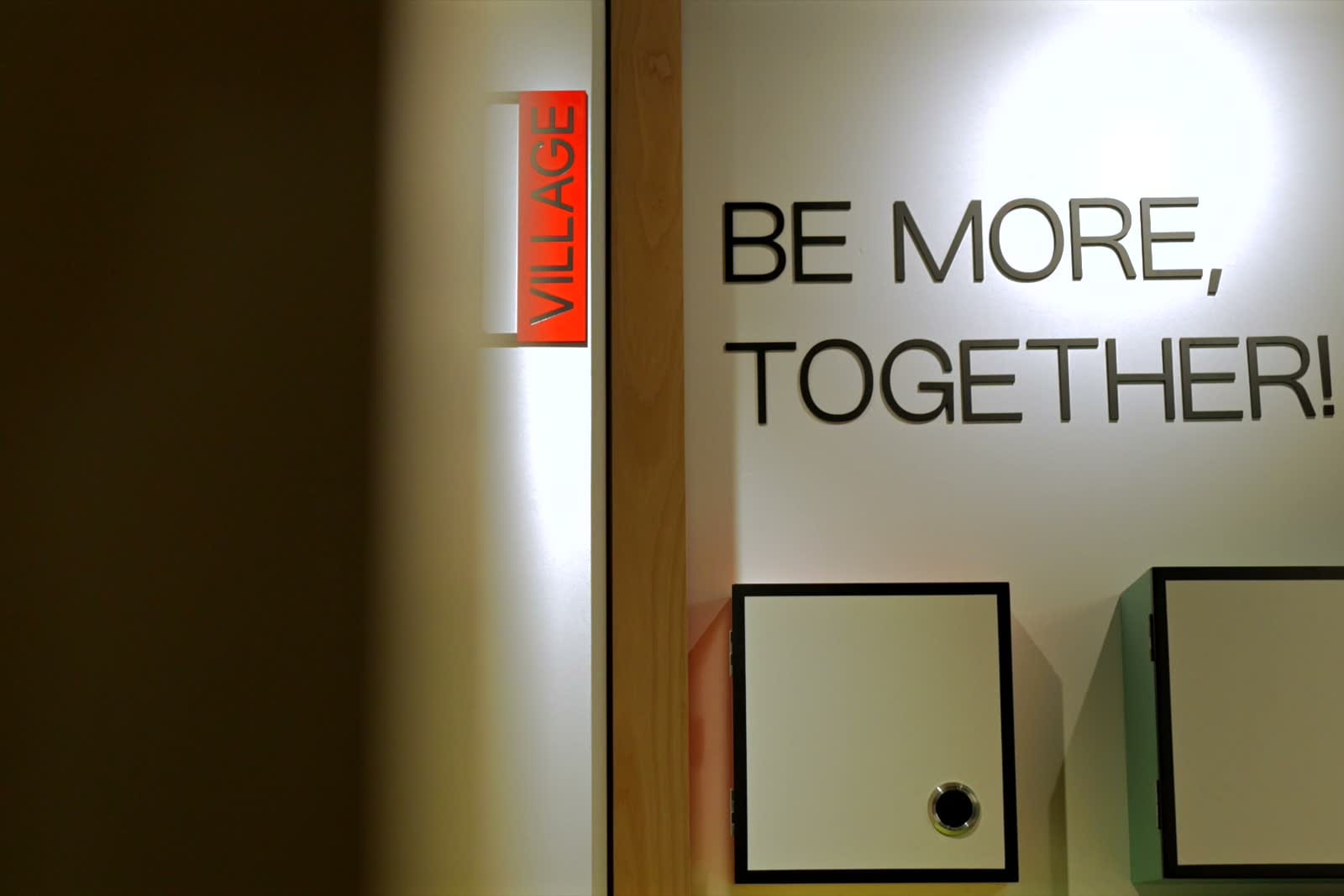 Dòng chữ Be more, together trên tường trong không gian Genesia.
