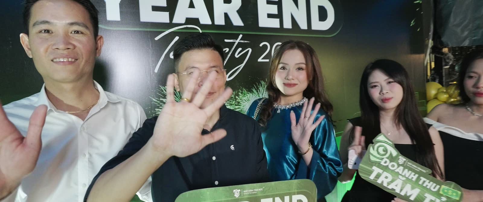 Khách mời đứng trước bảng Year End Party trong chương trình Mắt Kính Tâm Đức.