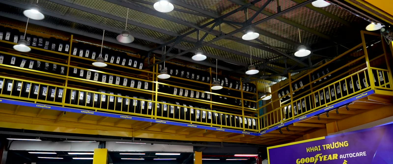 Nhìn lên tầng lửng xếp kín lốp xe Goodyear, bảng Khai trương Goodyear Autocare ở góc phải