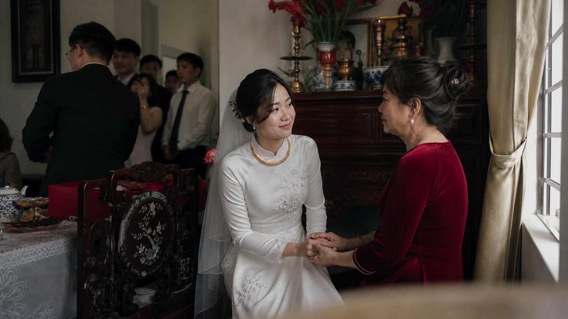 Cô dâu mặc áo dài trắng nắm tay mẹ trong lễ ăn hỏi tại nhà