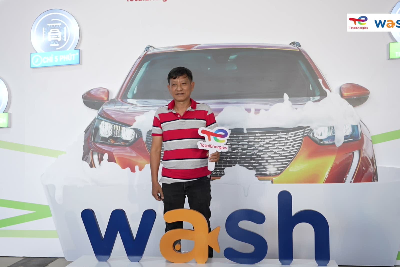 Khách mời đứng cạnh hình ảnh chiếc xe trên phông nền Wash.