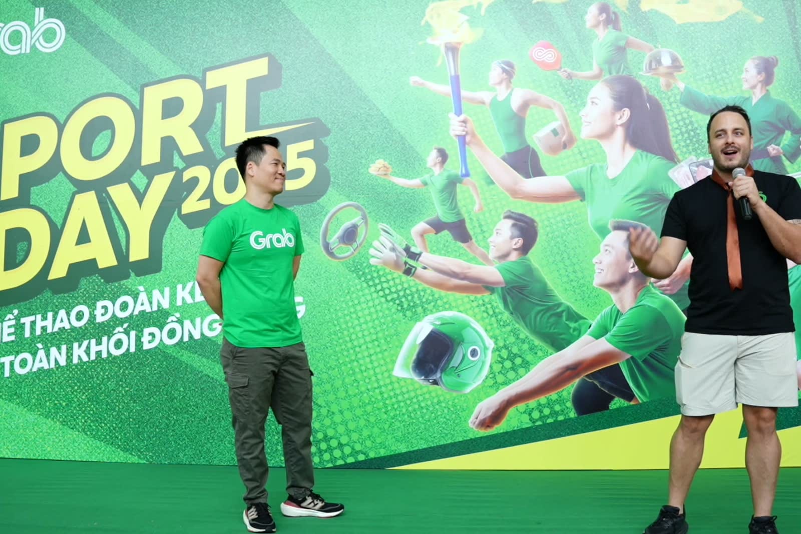 Người dẫn cầm micro trước bảng Grab Sport Day 2025.