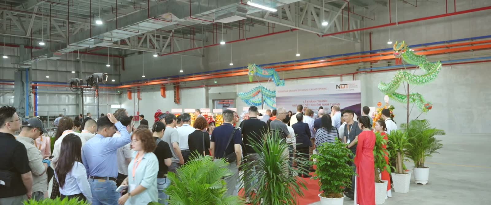 Khách mời tham quan bên trong nhà xưởng mới trong lễ khai trương, rồng trang trí treo hai bên