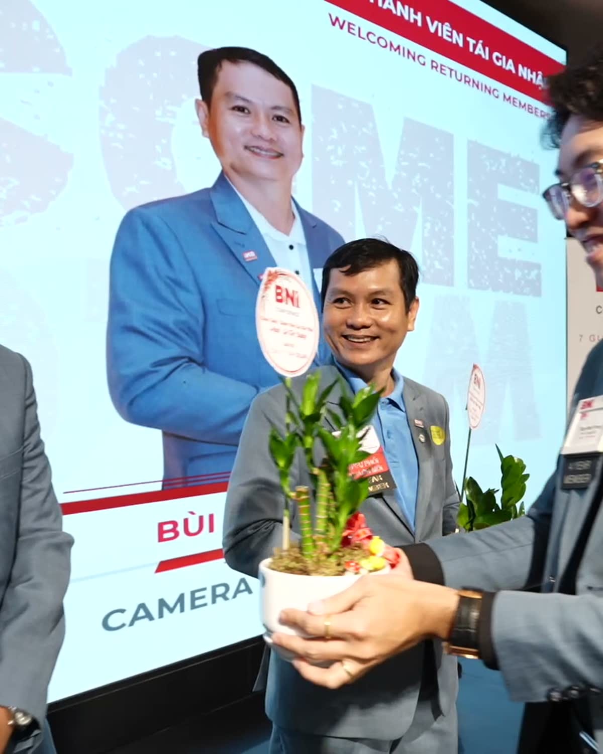 Thành viên BNI trao hoa và ghi nhận trước màn hình sự kiện.